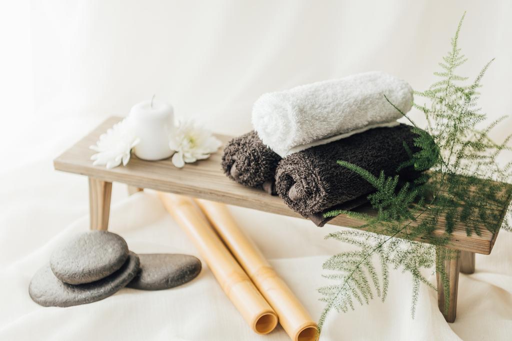 close up view of arrangement of spa treatment accessories with towels and pebbles on white background - Photo, Image