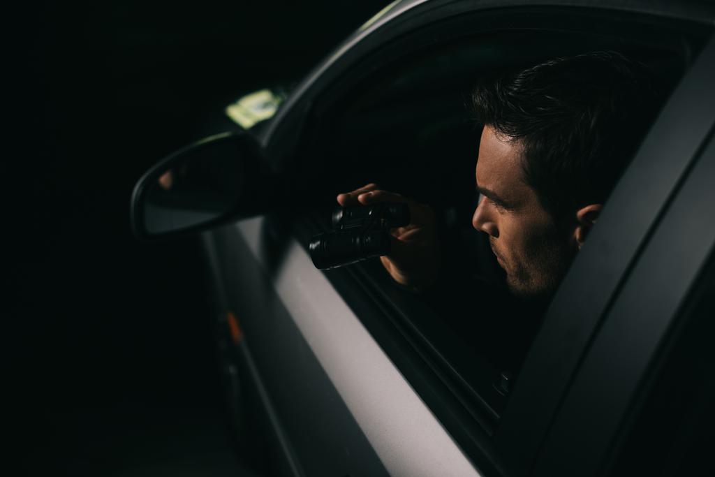 vue latérale de paparazzi mâle faisant la surveillance par jumelles de la voiture
  - Photo, image