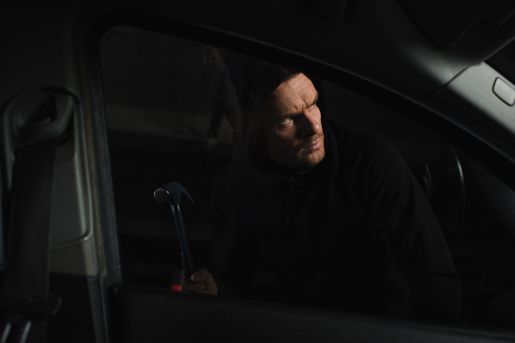 αρσενικό ληστής σε μαύρο hoodie απρόσκλητος αυτοκινήτου από ζευγάρι λαβίδες  - Φωτογραφία, εικόνα