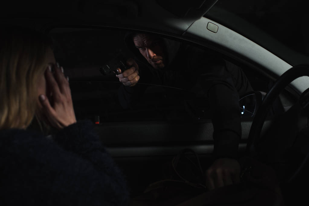 銃を目指して、車に座っている女性からバッグを盗んだ男性泥棒 - 写真・画像