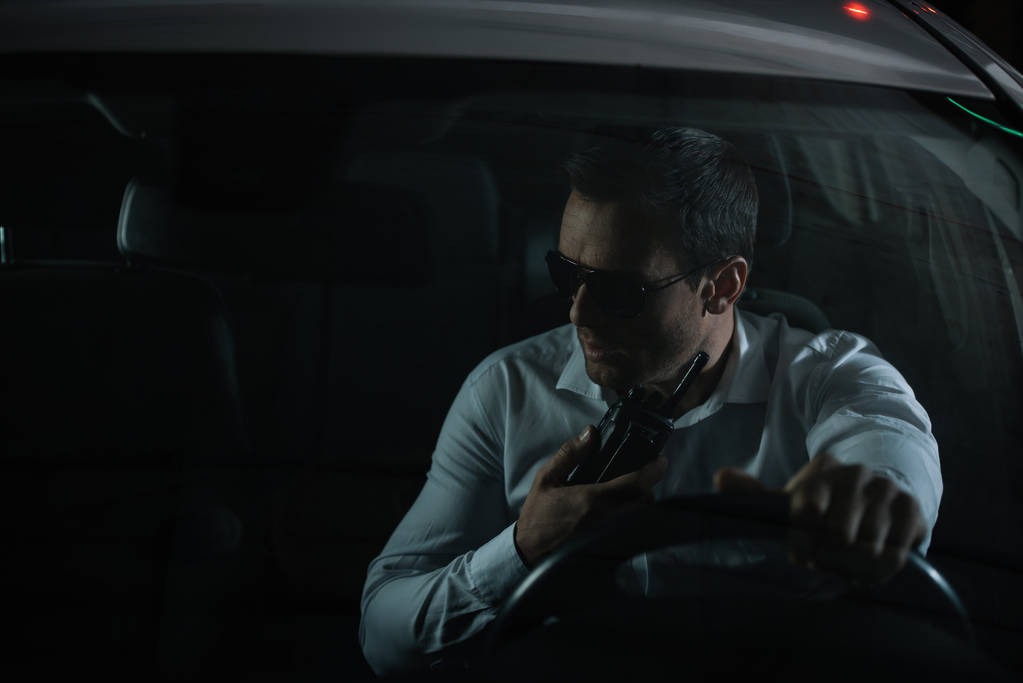 車の話のトランシーバーを使用してサングラスの深刻な男性捜査 - 写真・画像