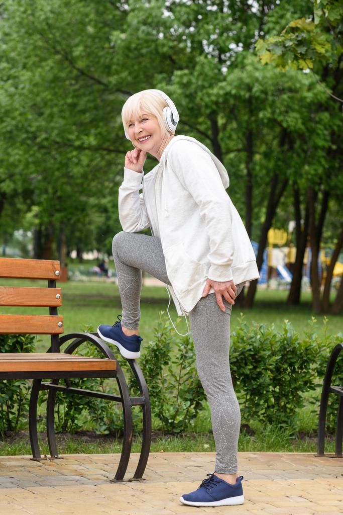 elderly sportswoman in headphones training in park  - Photo, Image