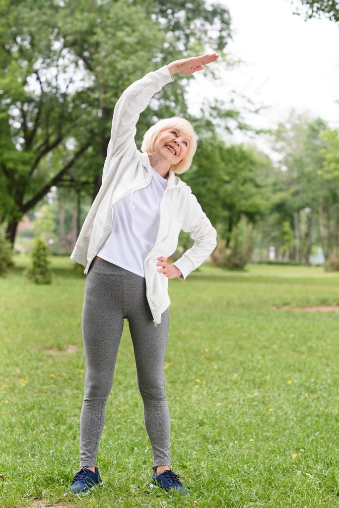 deportista de edad avanzada estirándose en el césped verde en el parque
 - Foto, imagen