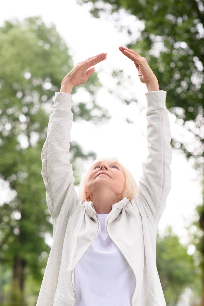 senior athletic woman exercising and stretching in park - Photo, Image