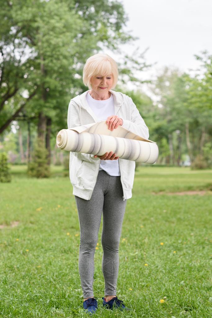 atlética mujer mayor con esterilla de yoga en el parque verde
 - Foto, imagen