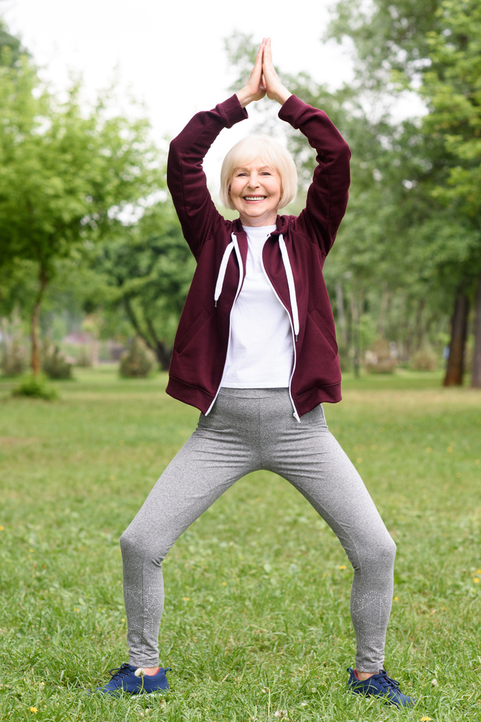 vanhempi nainen harjoittelee joogaa vihreällä nurmikolla
 - Valokuva, kuva
