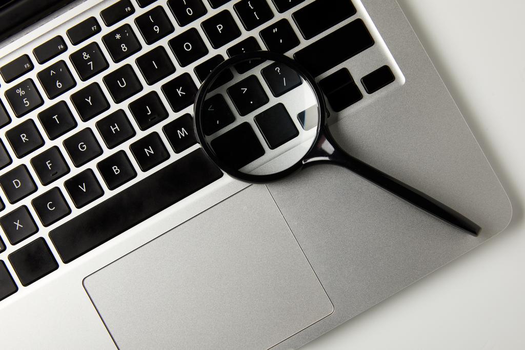 top view of magnifying glass and laptop on grey - Photo, Image