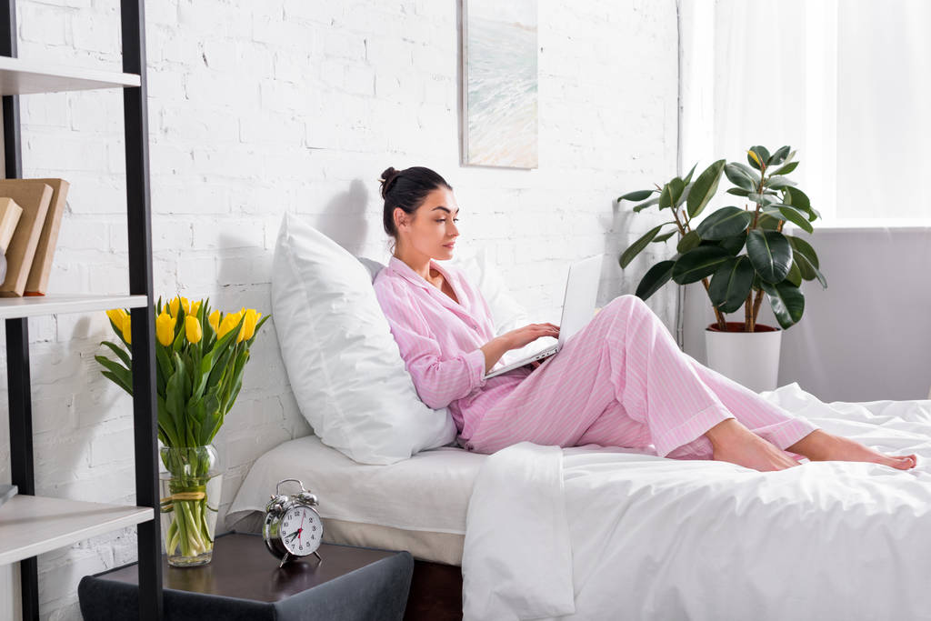 kadın evde yatakta dizüstü kullanarak pijama yan görünüm - Fotoğraf, Görsel