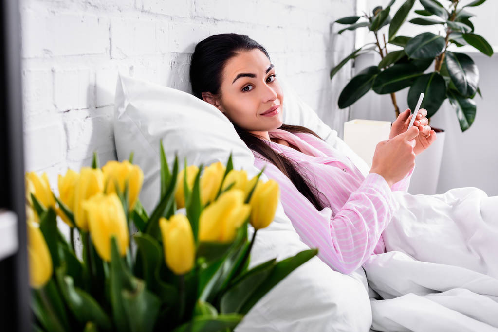 valikoiva painopiste houkutteleva nainen pyjama älypuhelin lepää sängyssä kotona
 - Valokuva, kuva