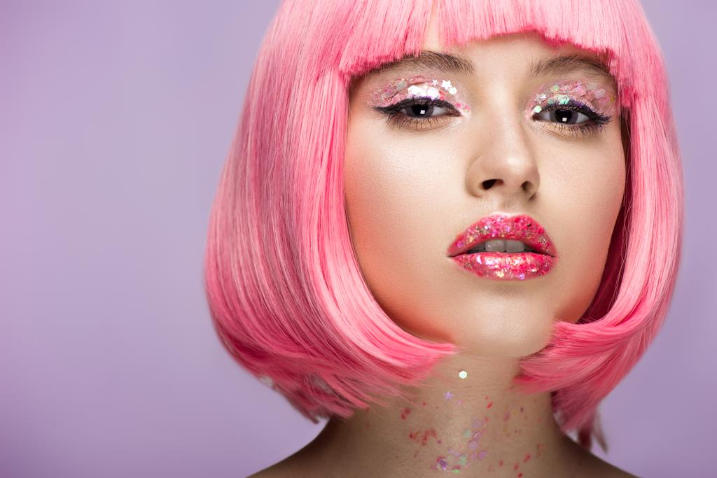 atraktivní žena s růžové vlasy a zářivě třpytivý make-up při pohledu na fotoaparát izolované na fialové - Fotografie, Obrázek
