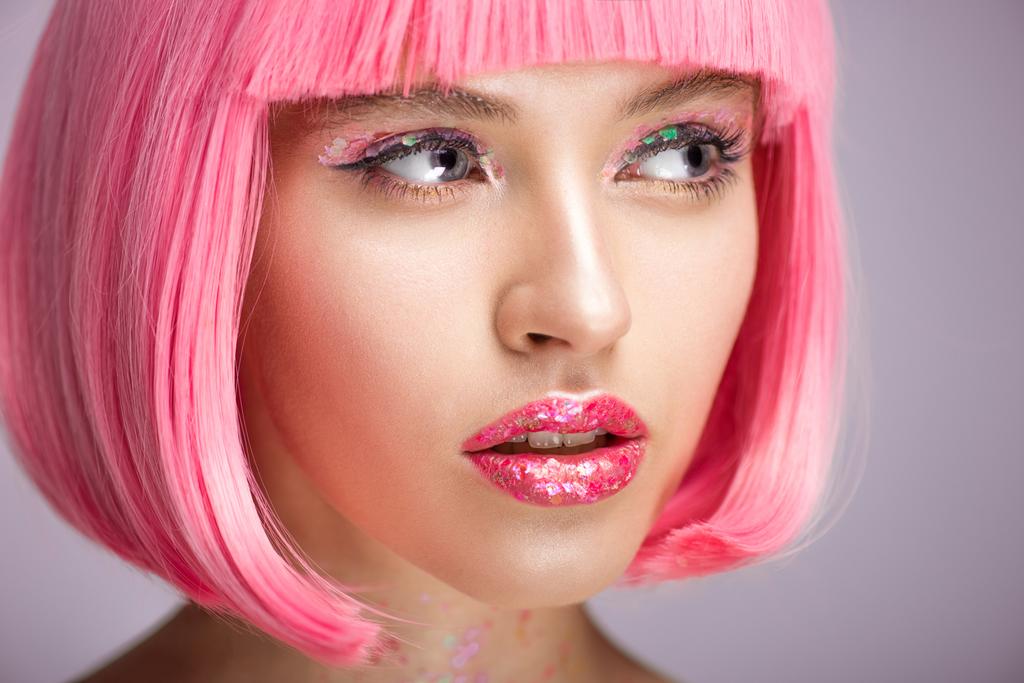 headshot του ελκυστική γυναίκα με ροζ μαλλιά και λάμψη στο πρόσωπο που ψάχνει μακριά απομονώνονται σε βιολετί - Φωτογραφία, εικόνα