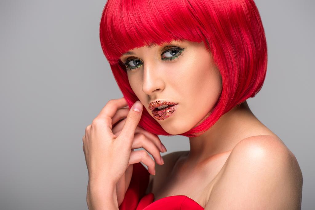 mulher atraente tocando cabelo vermelho e olhando para a câmera isolada no cinza
 - Foto, Imagem
