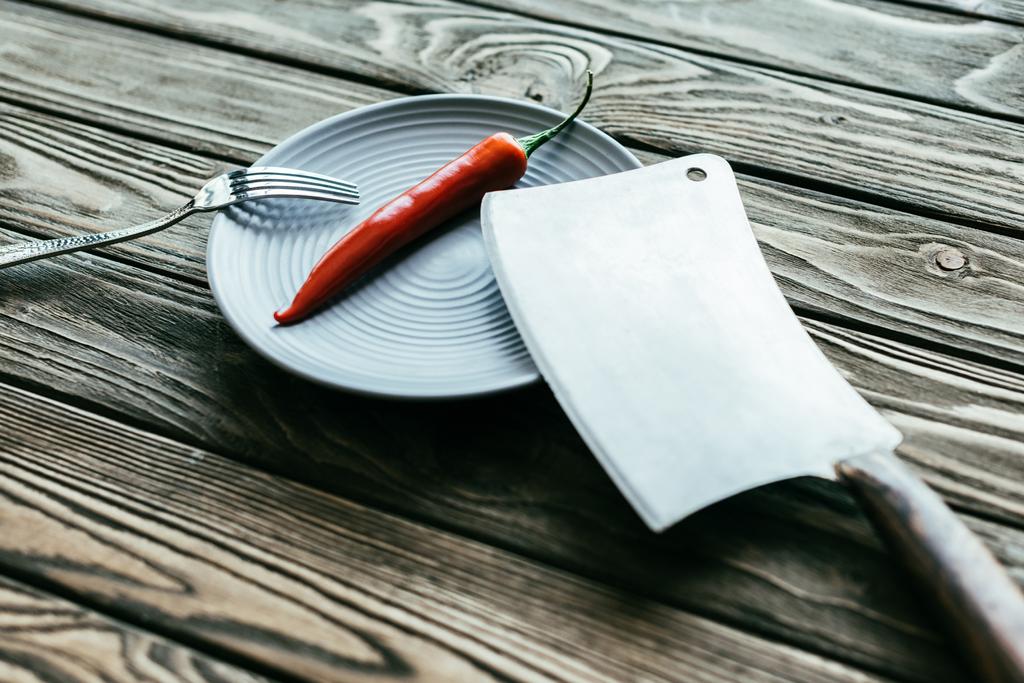 Blauw bord met chili peper en bestek op houten tafel - Foto, afbeelding