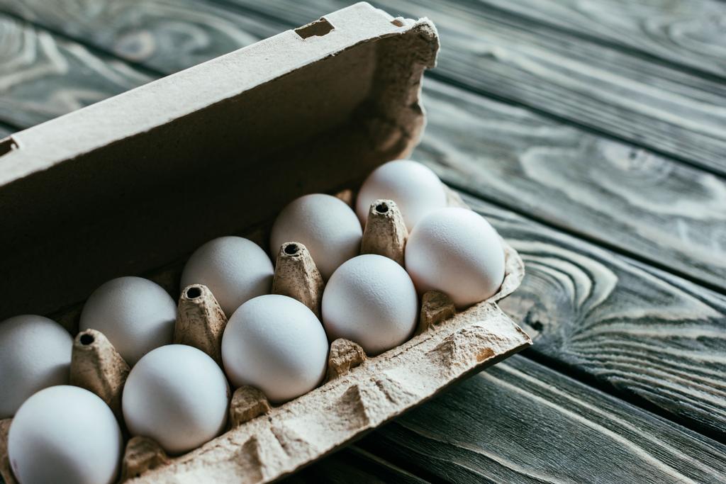Χαρτοκιβώτιο με άσπρα αυγά στο ξύλινο τραπέζι - Φωτογραφία, εικόνα