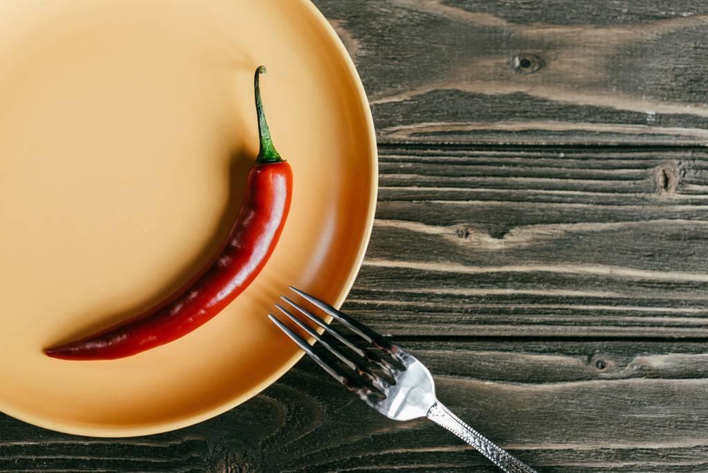 Ahşap masa üzerinde kırmızı biber ile tabağına çatal - Fotoğraf, Görsel