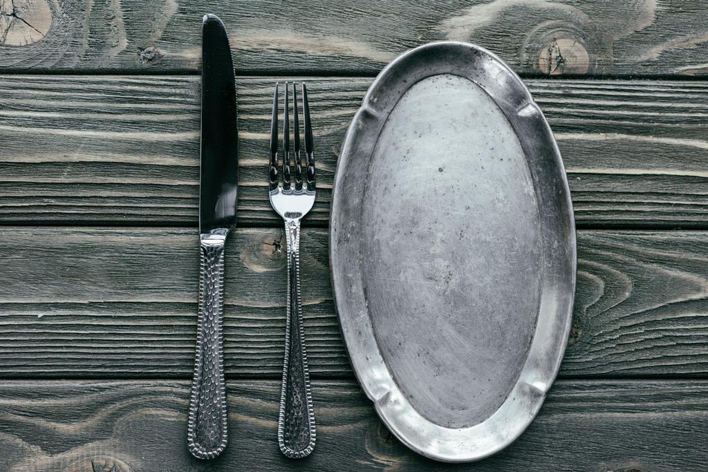 Μαχαίρι και πιρούνι με ασημένιο δίσκο στο ξύλινο τραπέζι - Φωτογραφία, εικόνα