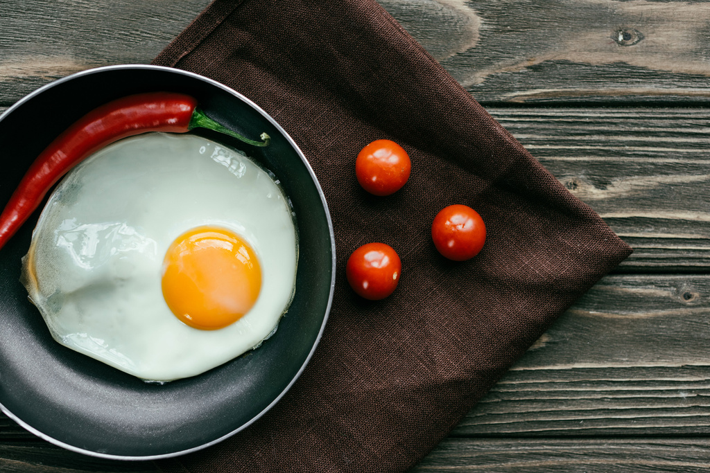 Сніданок зі смаженим яйцем та помідорами на текстильній серветці
 - Фото, зображення