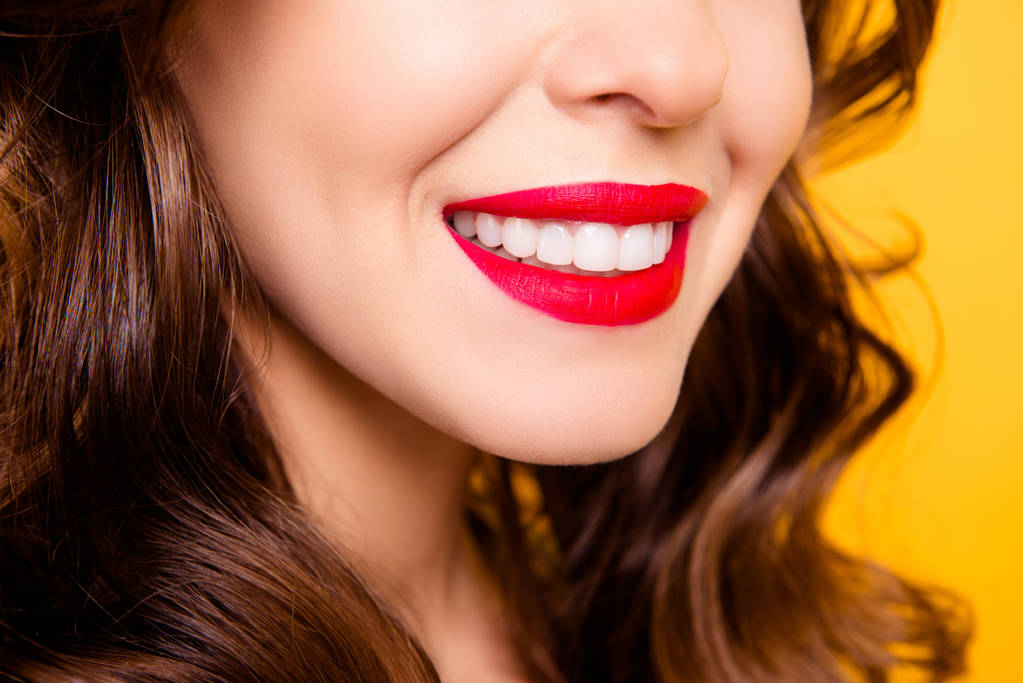 Крупним планом обрізаний портрет напівповернутої леді з блимаючою посмішкою білі здорові зуби, що мають червону помпезність ізольовані на жовтому фоні
 - Фото, зображення