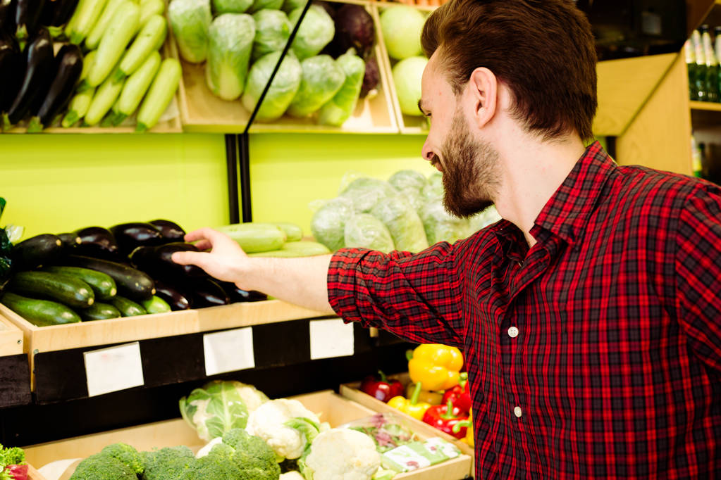 Καυκάσιος ο άνθρωπος σε κόκκινο καρώ πουκάμισο επιλογή λαχανικών σε σούπερ μάρκετ - Φωτογραφία, εικόνα