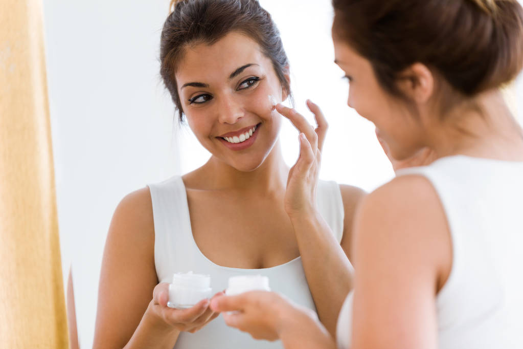 Aufnahme einer hübschen jungen Frau, die sich um ihre Haut kümmert und neben Spiegel im Badezimmer steht. - Foto, Bild