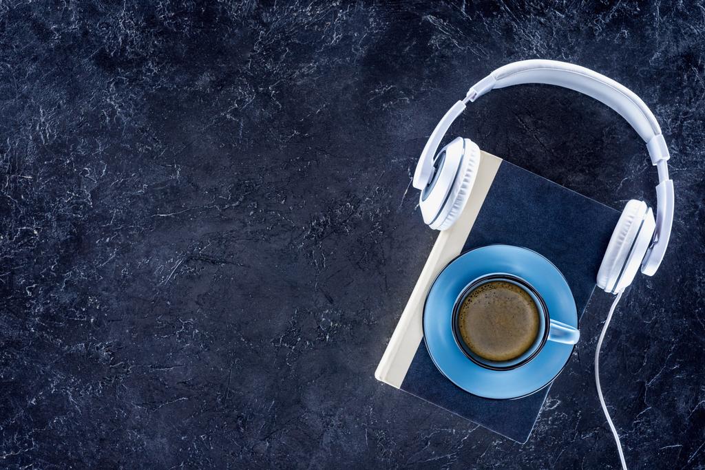 κάτοψη του βιβλίου, ακουστικά και μπλε φλιτζάνι με καφέ σε γκρι επιτραπέζια - Φωτογραφία, εικόνα