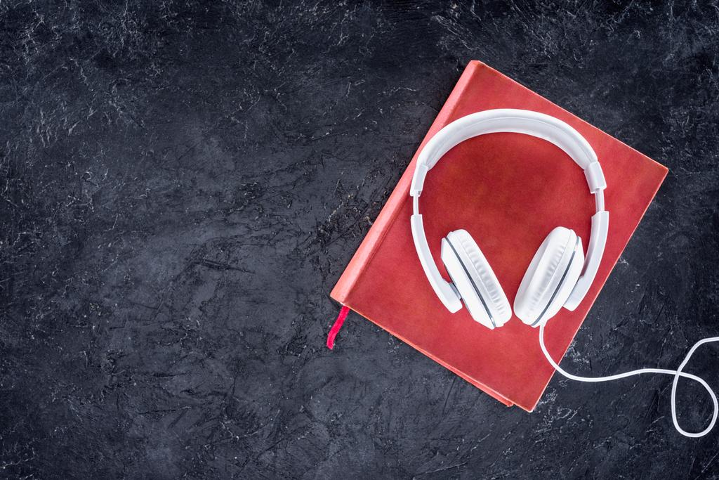 top view of red book and white headphones on grey tabletop - Photo, Image