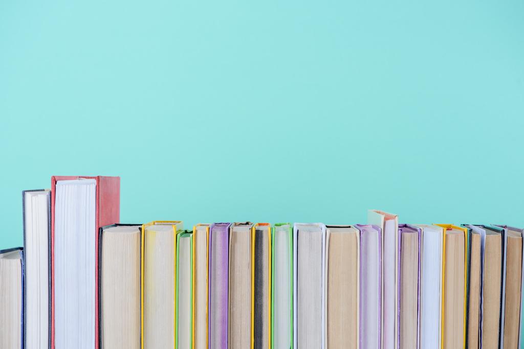 Reihe verschiedenfarbiger Bücher isoliert auf blauem Grund - Foto, Bild