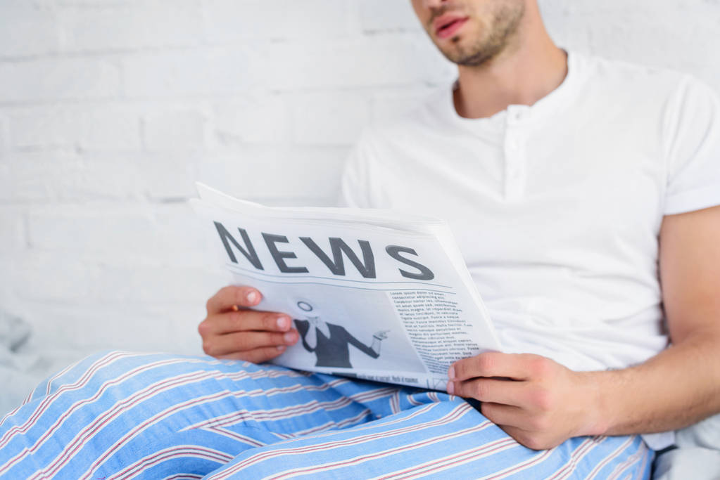 περικοπεί άποψη για τον άνθρωπο με τις πυτζάμες διαβάζοντας εφημερίδα στο σπίτι το πρωί - Φωτογραφία, εικόνα