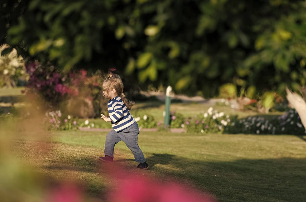Chico feliz divertirse. Chico correr sobre hierba verde en el jardín de verano
 - Foto, Imagen