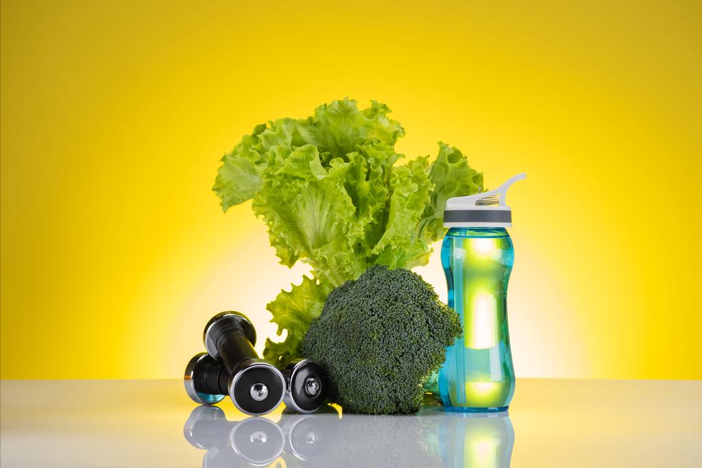 fresh green vegetables, bottle of water and dumbbells on yellow - Photo, Image