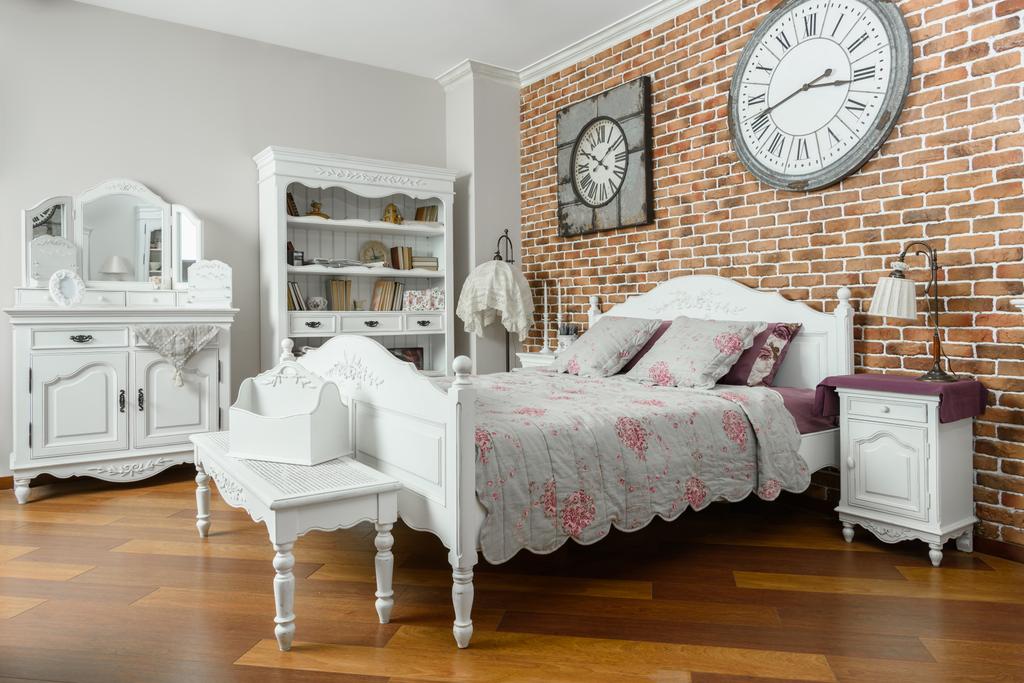 Interieur eines modernen hellen Schlafzimmers mit Wanduhren und Holzmöbeln - Foto, Bild