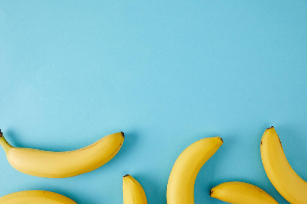 bovenaanzicht gearrangeerde verse bananen geïsoleerd op blauw - Foto, afbeelding