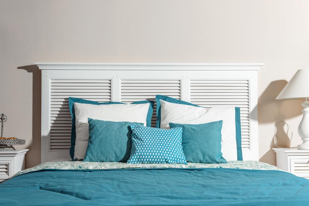 Interieur eines modernen Schlafzimmers mit weißem Holzbett und blauen Bettwäsche - Foto, Bild