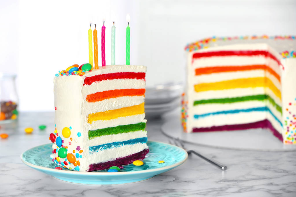 Delicious rainbow cake with candles for party on table - Zdjęcie, obraz