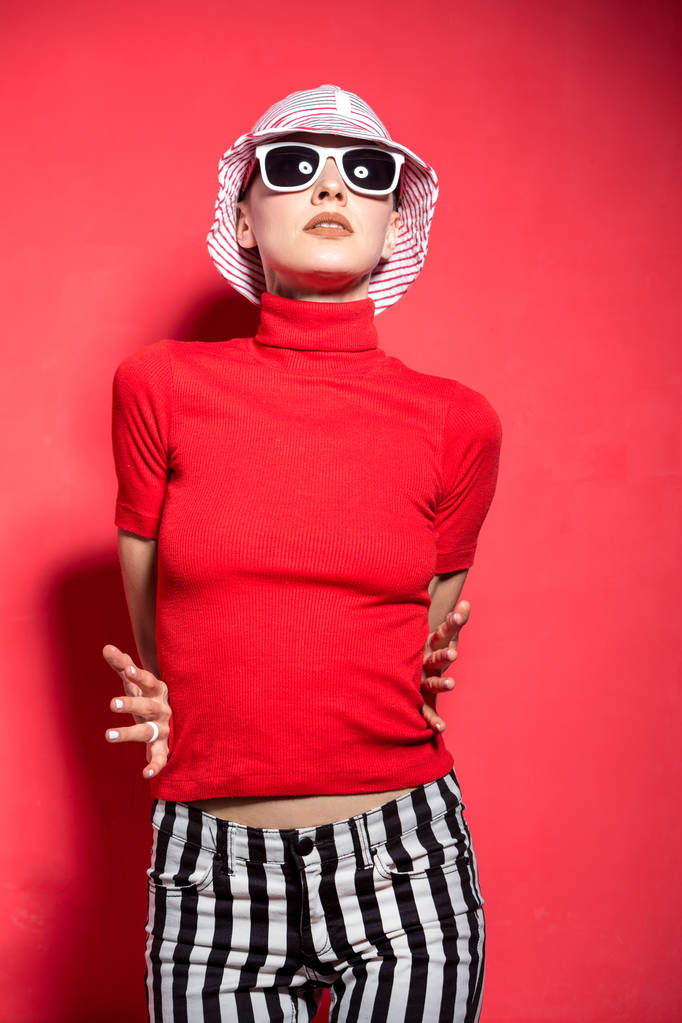 Чудова дівчина в сонцезахисних окулярах і капелюсі на червоному тлі
 - Фото, зображення