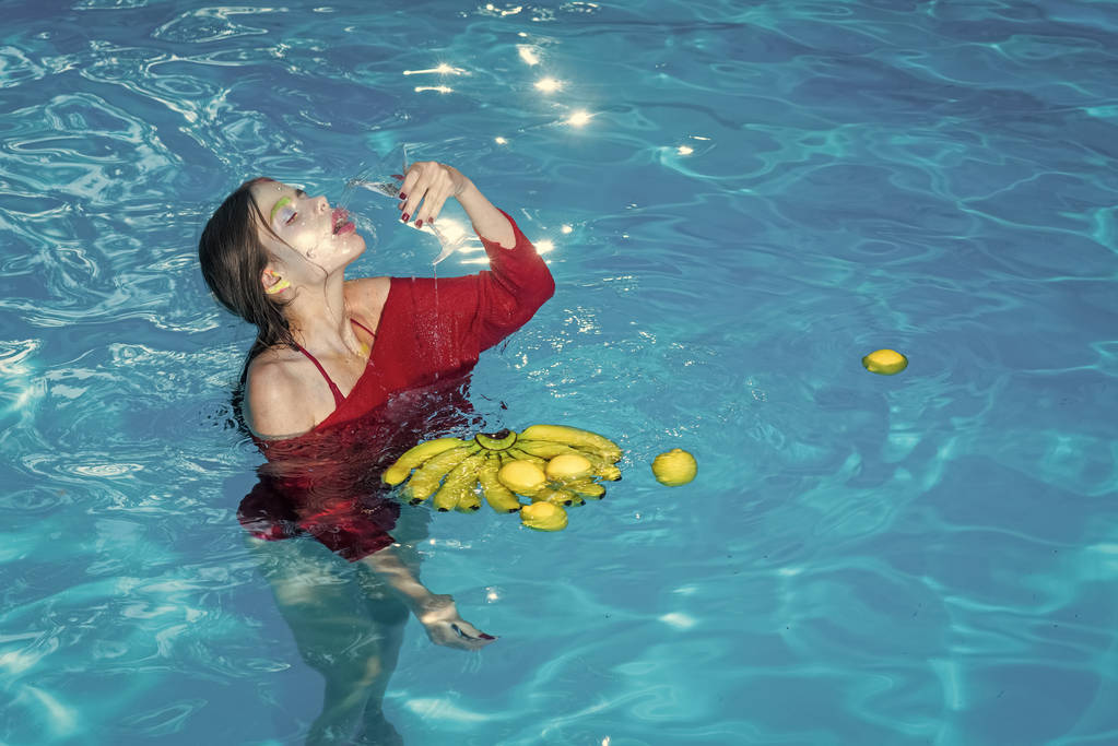 Moda kobieta modelu pozowanie. Witaminy w banana o dziewczyna siedzi w pobliżu wody. Relaks w basenie spa. Wakacje i podróże do oceanu. Zbilansowana dieta i zdrowe, wegetariańskie. Kobieta z - Zdjęcie, obraz