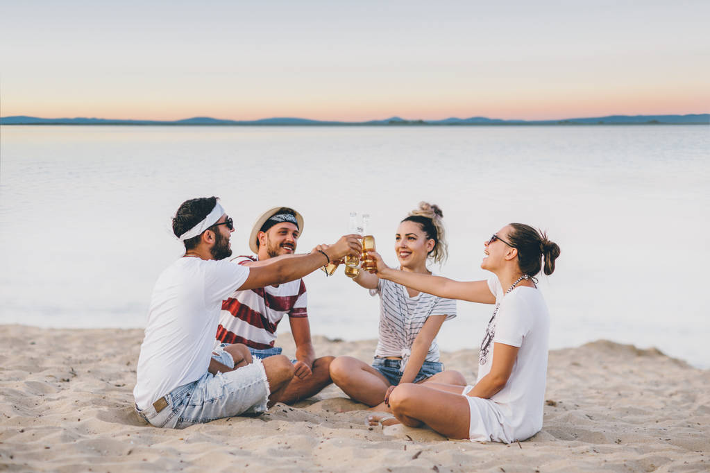 Groupe de jeunes gens heureux à la plage parlant et buvant des bières
 - Photo, image