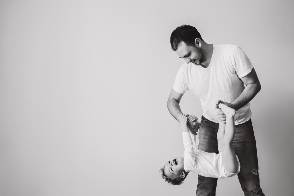 μαύρο και άσπρο φωτογραφία του πατέρα που παίζει μαζί με το μικρό του γιο στο σπίτι - Φωτογραφία, εικόνα