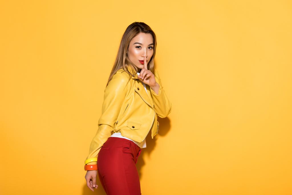 vonzó ázsiai női modell záró száj ujját sárga háttér  - Fotó, kép