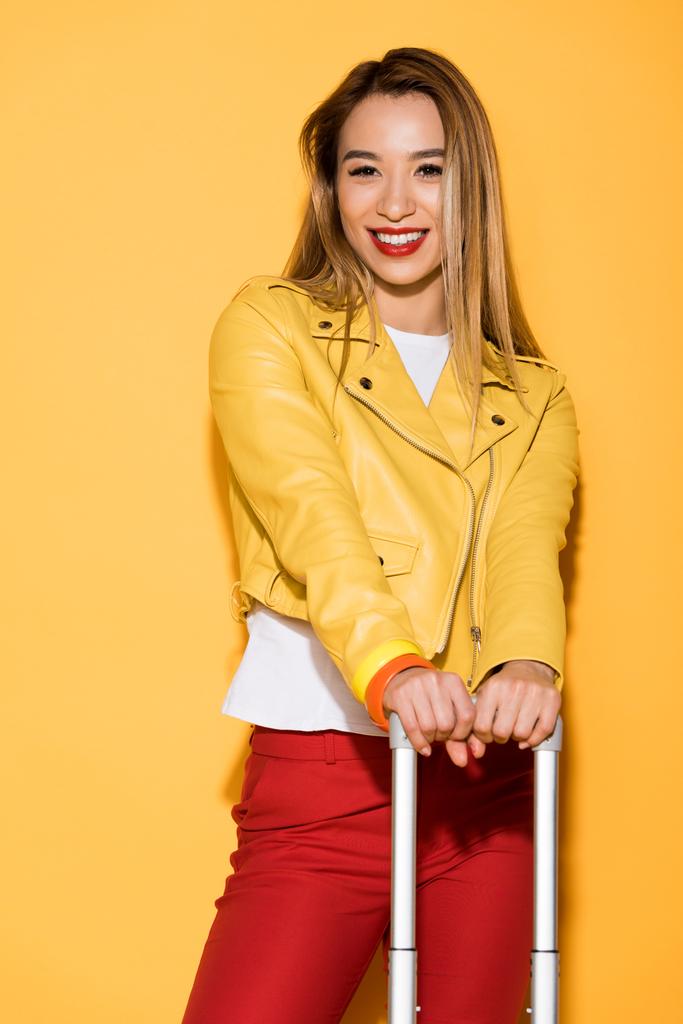 viajero femenino con estilo con bolsa de ruedas sobre fondo amarillo
  - Foto, imagen