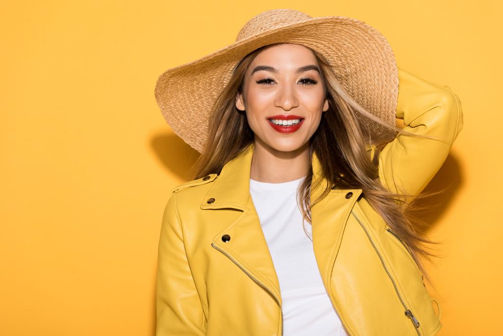 усміхнена стильна азіатська жінка в солом'яному капелюсі на жовтому фоні
  - Фото, зображення
