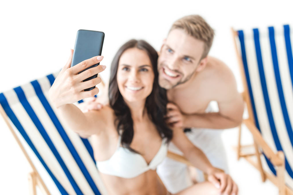 ビーチチェア、白で隔離をスマート フォンと selfie のカップルの選択と集中 - 写真・画像
