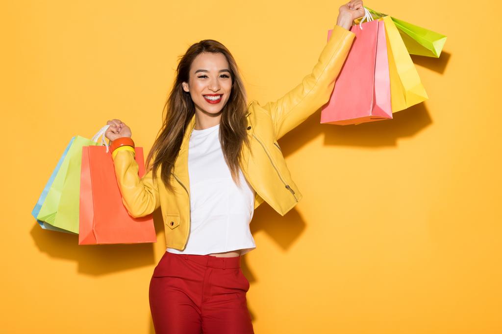 усміхнена азіатська жінка з сумками на жовтому фоні
  - Фото, зображення