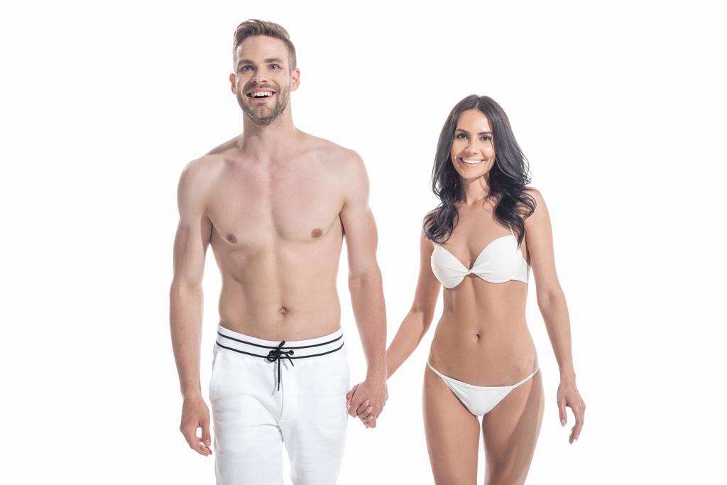 krásný veselý pár v plavky drží za ruce, izolované na bílém - Fotografie, Obrázek