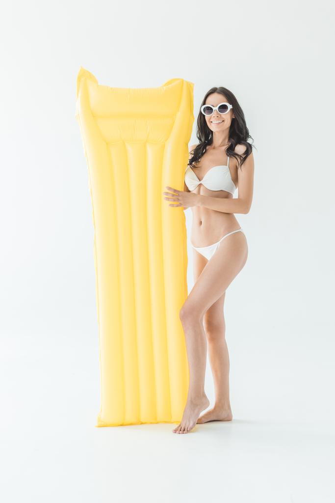 vonzó nő-ban bikini kérdésekkel zavarba hozó a sárga felfújható matrac, elszigetelt fehér - Fotó, kép