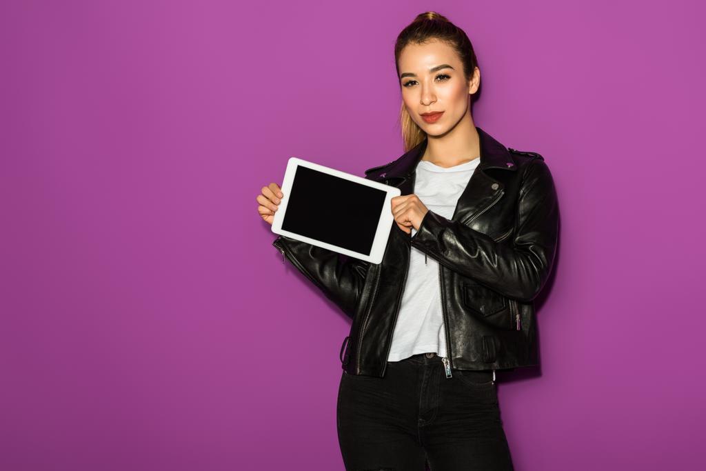 kaunis nuori aasialainen nainen tilalla digitaalinen tabletti tyhjä näyttö ja katsot kamera eristetty violetti
 - Valokuva, kuva