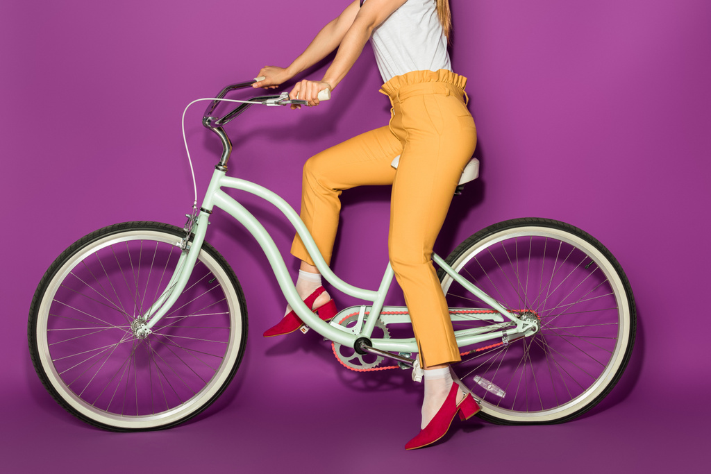 tiro cortado de menina elegante andar de bicicleta isolada em violeta
 - Foto, Imagem