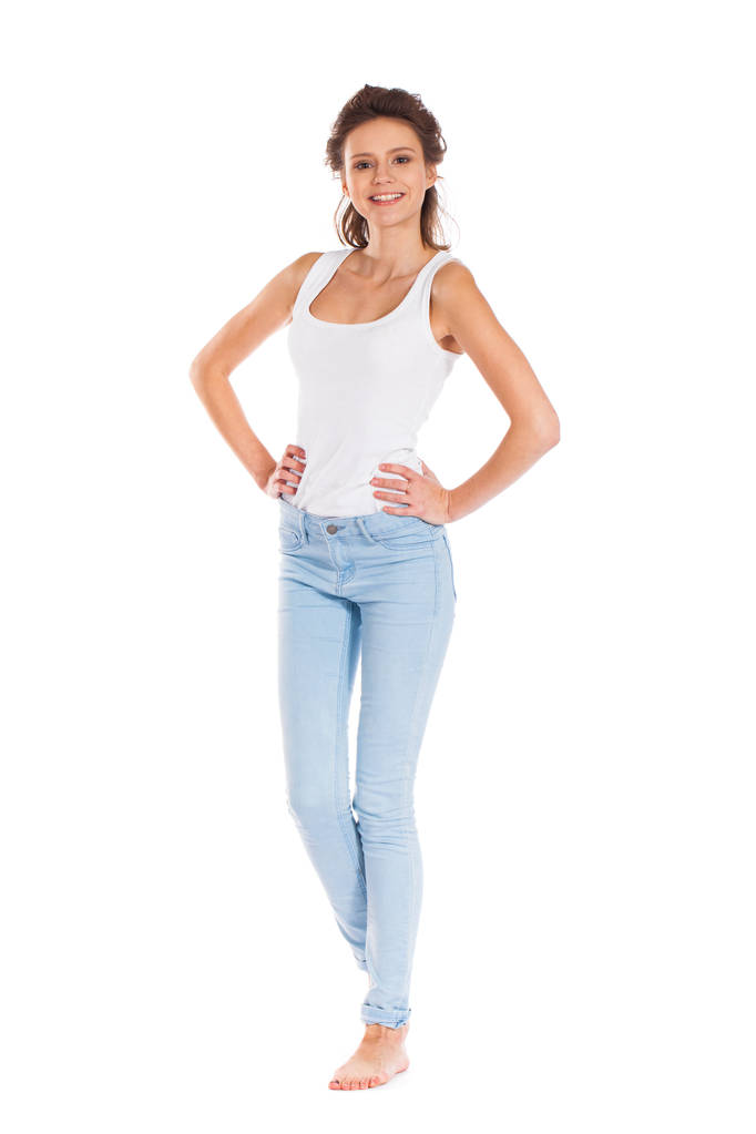 Портрет усміхненої милої молодої жінки в блакитних джинсах, що стоїть ізольовано на білому тлі
 - Фото, зображення