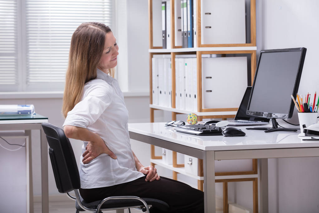 Widok boczny Dorosła kobieta siedzi na krześle, cierpiących na bóle pleców - Zdjęcie, obraz