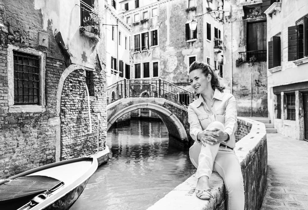 Feliz joven sentada en el puente en Venecia, Italia y mirando canal
 - Foto, imagen